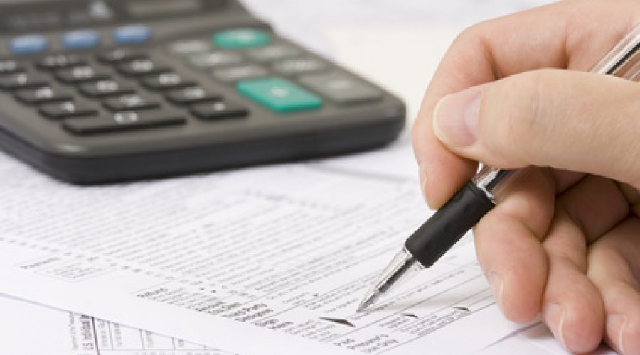 Close-up of a hand with a pen filling out tax form